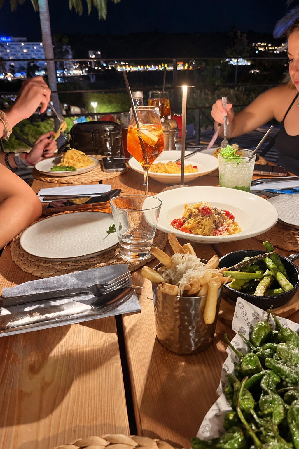 Friends sharing food and drinks around an outdoor dinner table